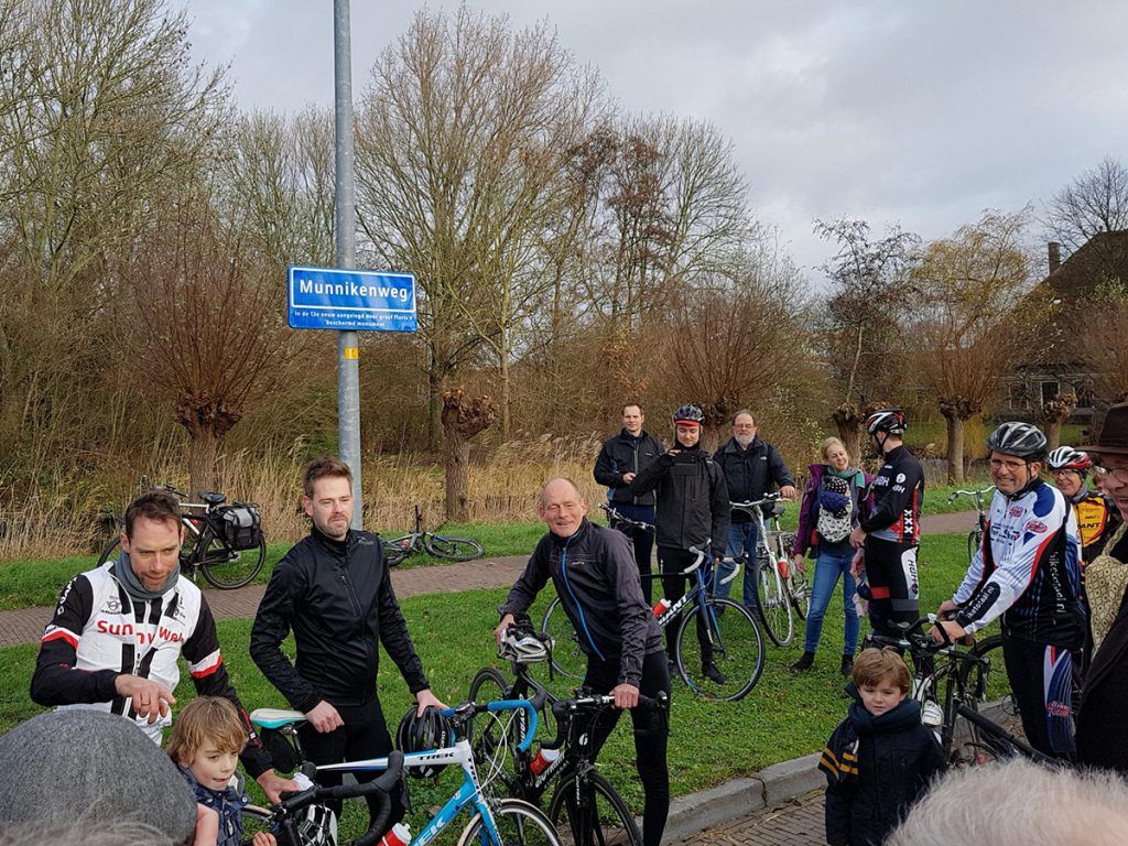 Een van de nieuwe straatnaamborden langs de Munnikenweg onthuld door raadslid Willem Peters (BAS) (l), Laurens ten Dam (m) en op de rug gezien wethouder Erfgoed Christian Braak.