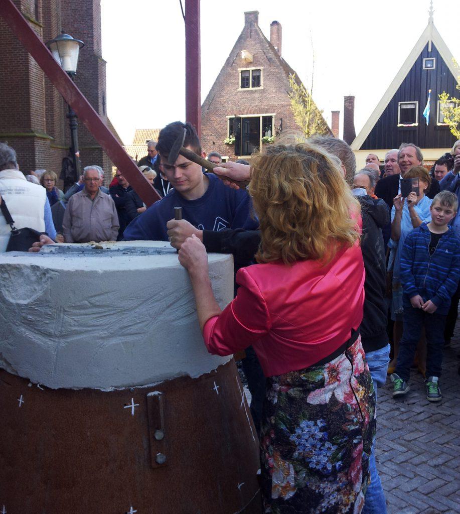 Wethouder Anjo van de Ven onthult de zojuist gegoten klok. Naar een oud gebruik had zij van tevoren in de smeltkroes een messing ‘geluksmunt’ geworpen.