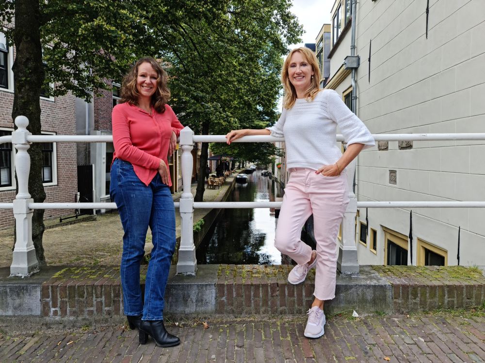 Nancy de Jong en Simone van der Vlugt met uitzicht op de Kooltuin, een dertiende-eeuws stukje Alkmaar. Simone: "Hier laat ik ook mijn personages langs komen met hun voertuig 