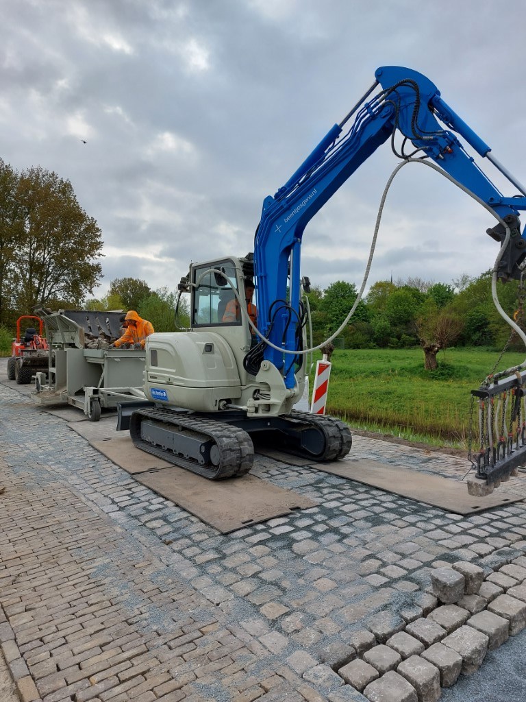 Het herstraten van de Munnikenweg gebeurt met een speciale machine