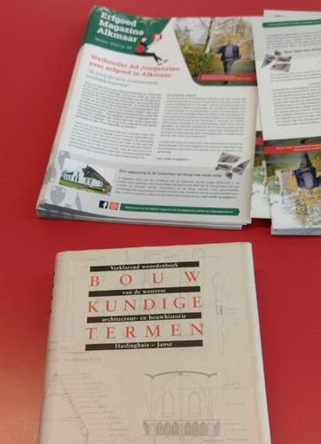 Een erfgoedmagazine met daaronder het boek waarin een afbeelding gezocht moest worden voor de volgende editie van het magazine