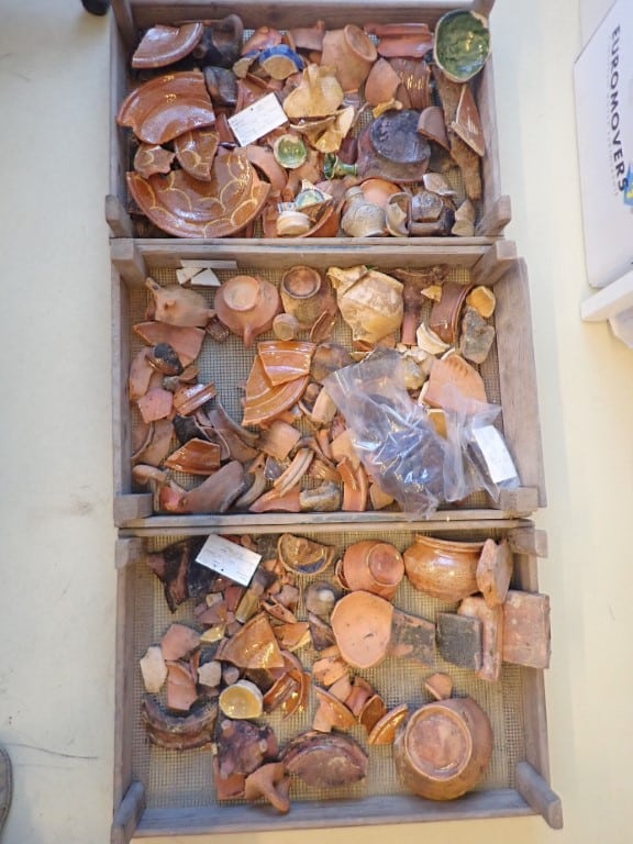 Drie kratten met aardewerk uit de Boterstraat dat na het spoelen ligt te drogen . In het bovenste krat enkele fragmenten blauw tinglazuur van een zogeheten malling jug