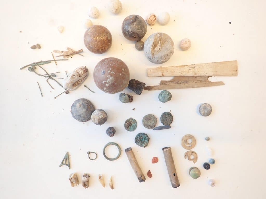 Kleine dingen zoals spelden, naalden, kralen en munten, gevonden in een beerput aan de Langestraat 106