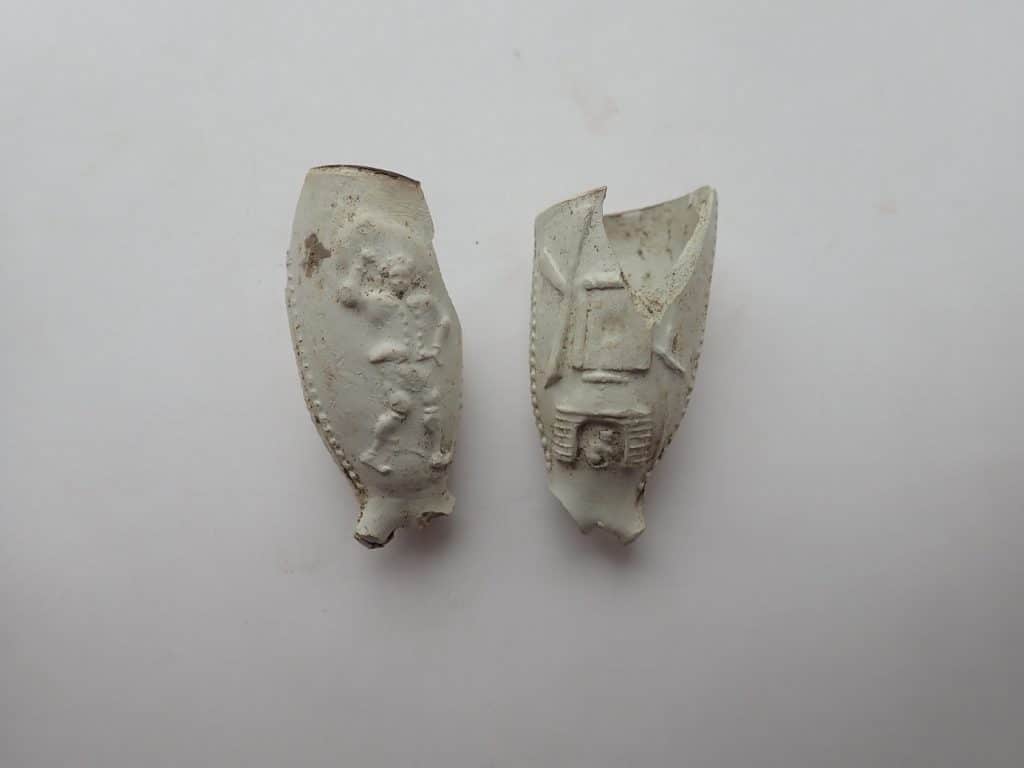 Twee identieke versierde pijpen uit het begin van de achttiende eeuw met in reliëf aan de ene kant een zakdrager en aan de andere kant een zogenoemde standaardmolen
