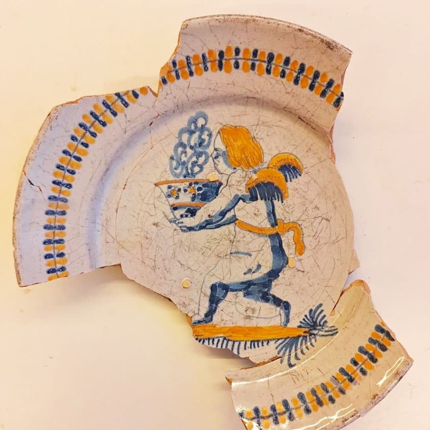 Majolica schotel uit de zeventiende eeuw met een cherubijn met een kom met dampende inhoud.