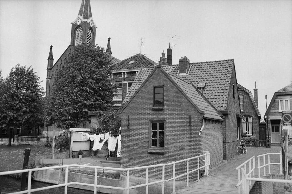 De Rijp begin 1970. De Grote Kerk op de achtergrond. Op de voorgrond het vaste bruggetje van het Langebrugspad, inmiddels vervangen door een ophaalbrug. Daarachter het woonhuis annex tabakszaak van Piet Berkhout, Rechtestraat 91. Op het plaatsje van 91 hangt de was aan de lijn.