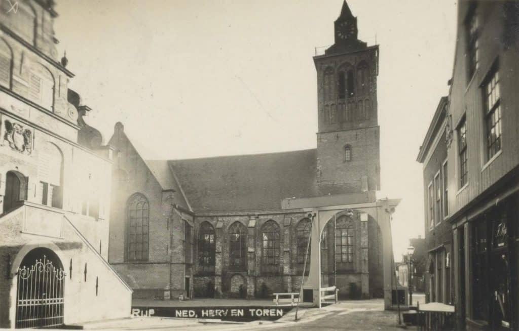 Prentbriefkaart van de Grote Kerk De Rijp. Circa 1930. Collectie Kaptein. Achter een raam van het eerste pand rechts is nog te lezen: F. Rijkes, en: margarine.