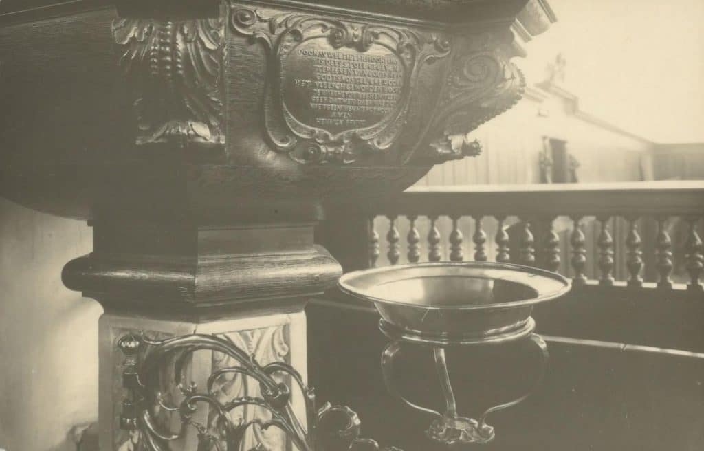 De voet van de preekstoel in de Grote Kerk van De Rijp. Rechts ervan het doopvont. Circa 1938. P. Delemarre. Collectie Kaptein.