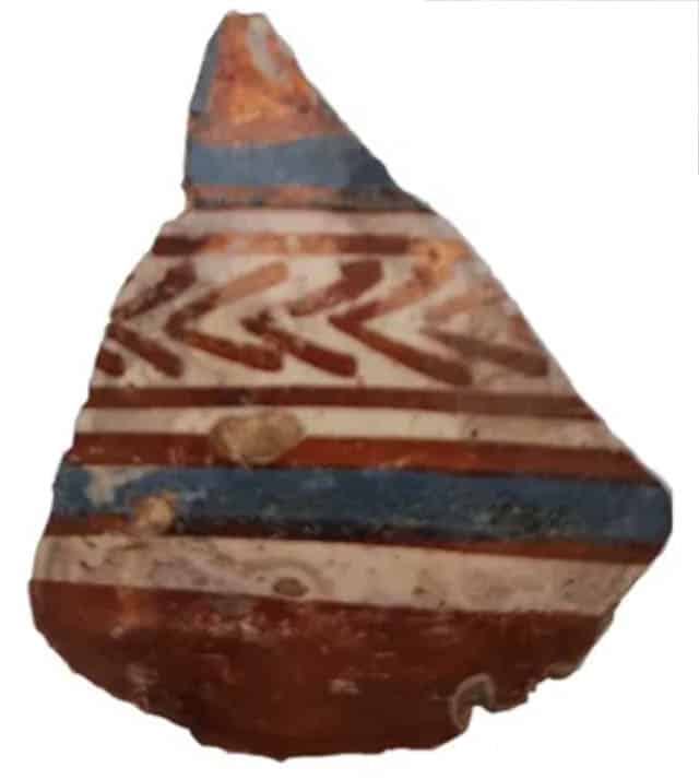 De scherf heeft aan de buitenzijde een laagje wit tinglazuur. Met geometrische versieringen in koperbruin (rood) en kobaltoxide (blauw).