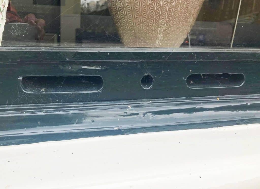 In de houten onderdorpel van het raam zijn afwisselend ventilatiesleuven en ventilatiegaten aangebracht.