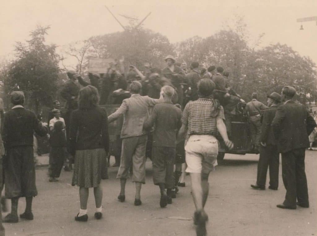 Bevrijding Alkmaar 1945. Op de achtergrond de wieken van de Molen van Piet. Hoek Kennemersingel met Kennemerstraatweg. Arrestanten worden door leden van de Binnenlandse Strijdkrachten vervoerd per open laadbak richting Heilooërbrug. Vermoedelijk om naar het politiebureau te gaan. Foto PJ Bosman Mei 1945.
