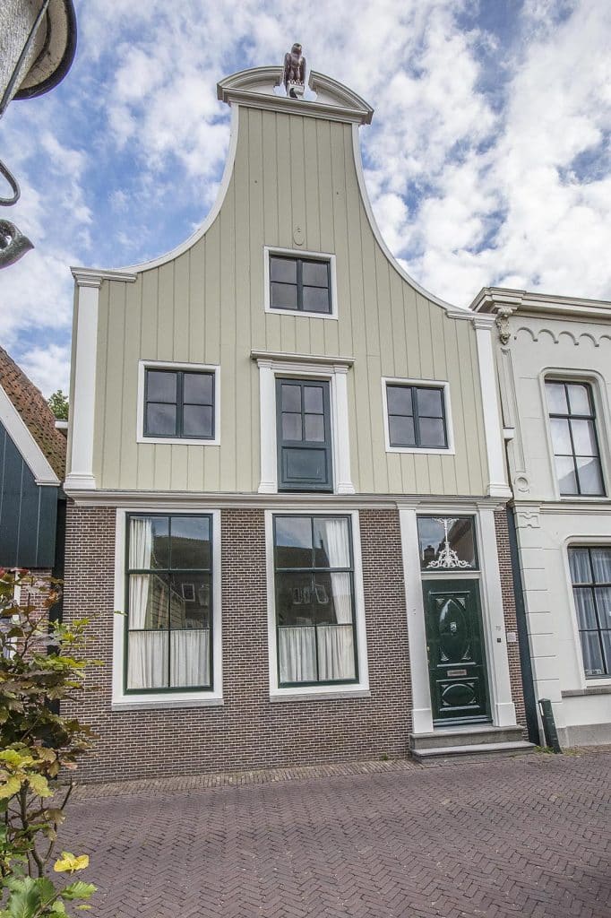 Het huis heeft een klokgevel. Bovenop de klokgevel staat een gebogen timpaan. Zo’n timpaan gebruikten de Grieken al om een klassiek gebouw af te sluiten.