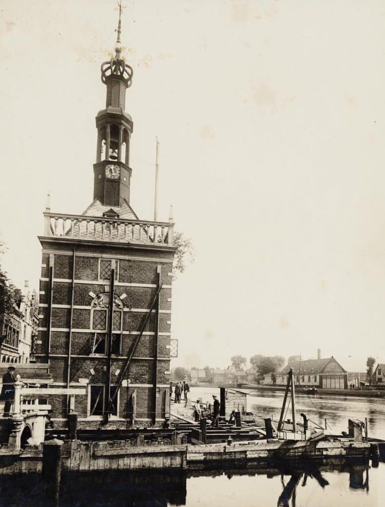 Accijnstoren tijdens de voorbereidende werkzaamheden voor de verrolling. Geheel rechts over het water Scheepswerf Nicolaas Witsen. Hollandia fotobureau 1924.