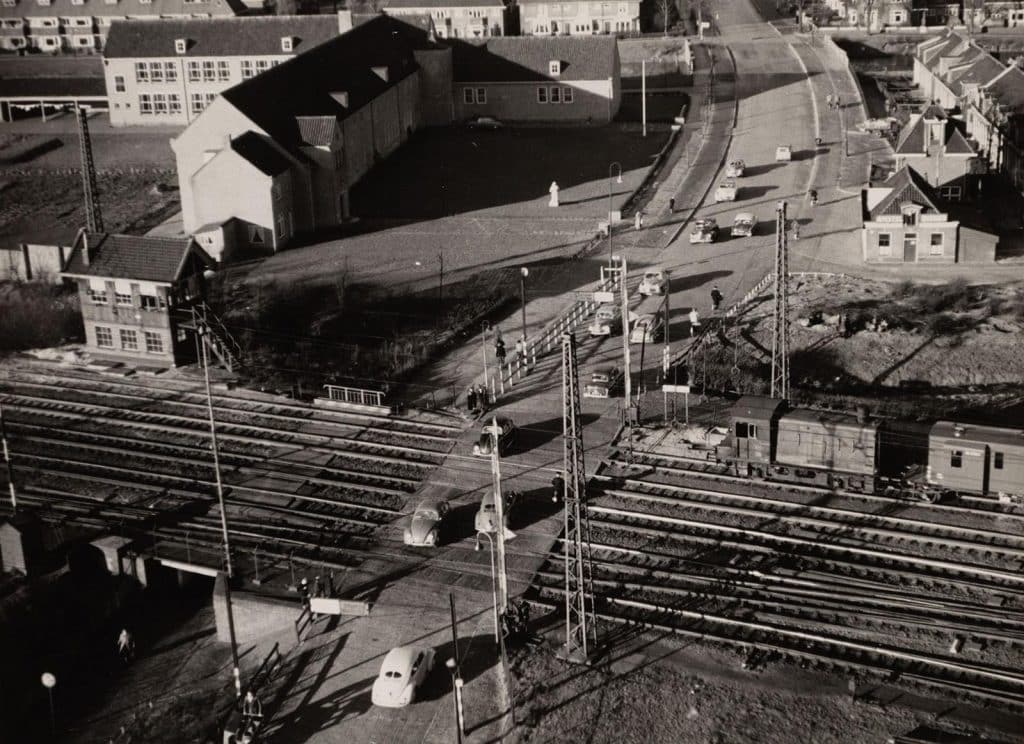 De spoorwegovergang gezien vanaf de watertoren in 1954. Links de Middelbare Landbouwschool. Bovenaan huizen aan de Nicolaas Beetskade. De voormalige Ambachtsschool staat net niet op deze foto. Die staat een stukje voor de sporwegovergang linksonder.