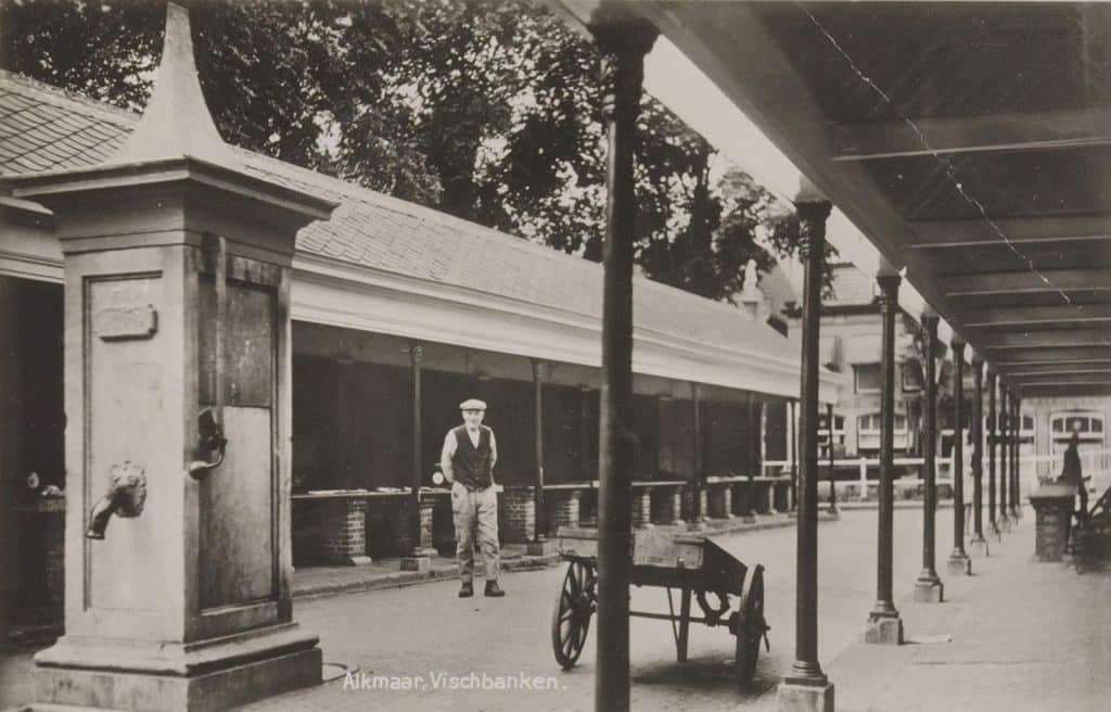Prentbriefkaart van een man, waarschijnlijk een visser, die poseert visbanken. Circa 1932.