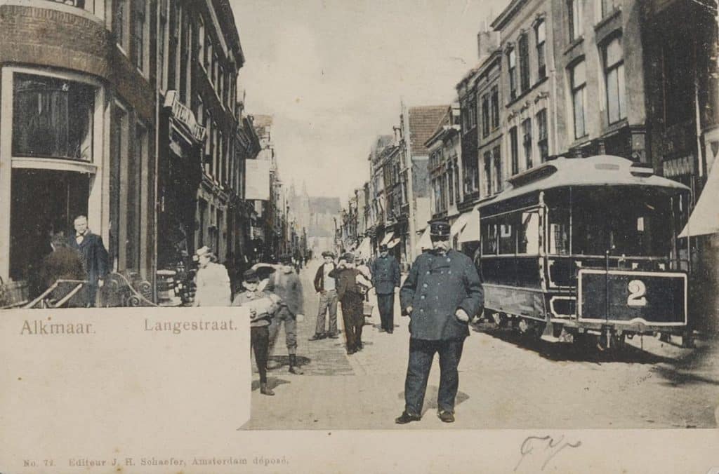 Prentbriefkaart van de Langestraat 1 hoek Mient met de apotheek. De paardentram lijn 2 staat klaar. In de verte de Grote Kerk Alkmaar. Circa 1902.