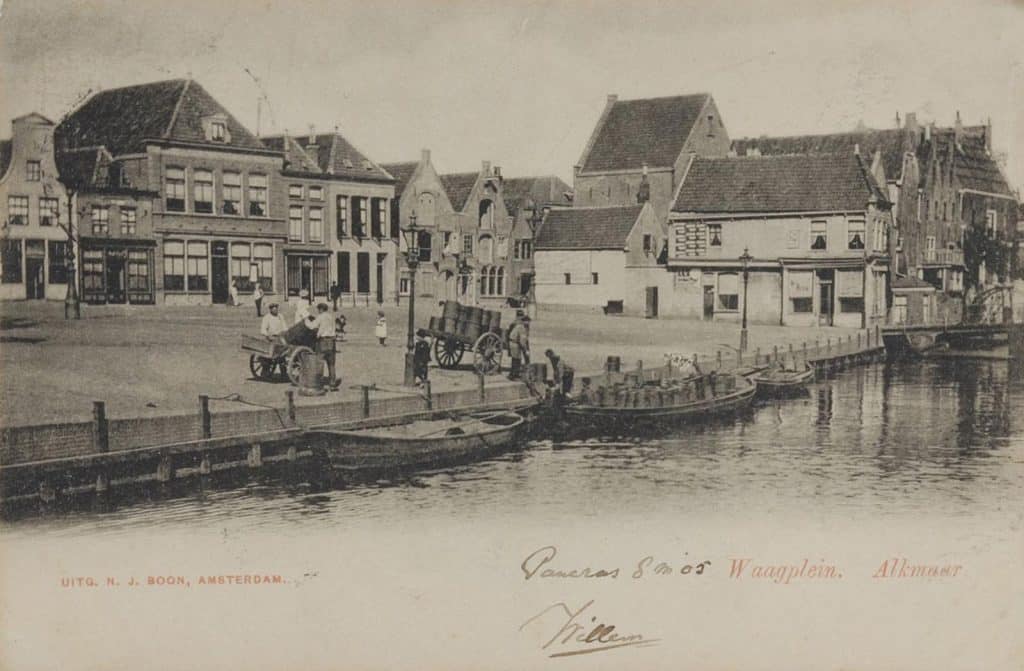 Prentbriefkaart helemaal rechts bierbrouwerij de Boom. Circa 1904. Het Waagplein, waar de tonnetjes met de kar werden aangevoerd. En per schip naar de eindbestemming werden gebracht. Rechts twee huizen tussen de Houttil en de Korte Mient. Voorheen de noordkant van de Moordenaarssteeg, met aan de rechterkant 't Klompje Goud(s). Ter vergroting van het Waagplein tussen 1908 en 1910, werden de huizen aan de noordkant van de Moordenaarssteeg gesloopt. Achter deze huizen werd in 1905 kaaspakhuis de Nationale Coöperatieve Zuivelverkoopcentrale gebouwd. Bierbrouwerij de Boom, uit 1647, werd daar in 1905 ook onderdeel van.