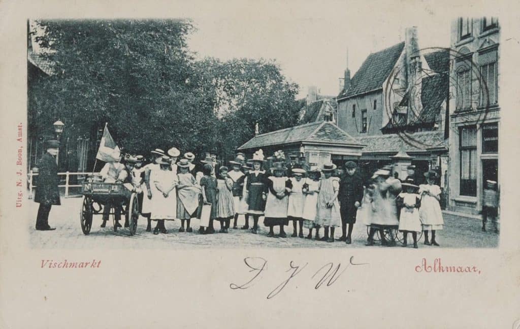 Prentbriefkaart van kinderen die poseren voor de fotograaf. Rechts de Visbanken. Circa 1903.
