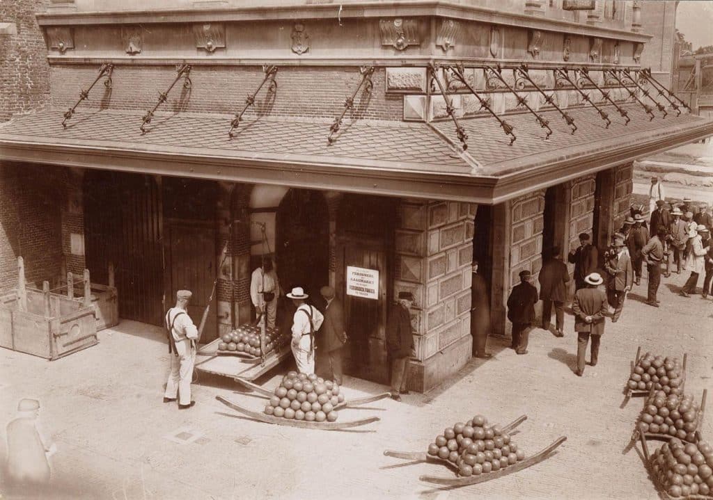 De Waag aan het gebouw een bord met de mededelingen Verboden Fooien te geven. Circa 1900.
