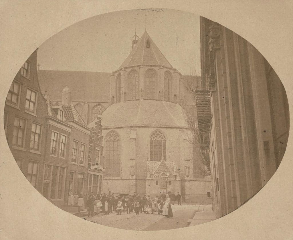 Gezicht op de Langestraat hoek Koorstraat bij de Grote Kerk. Op de hoek de zaak van J.C. Faerber huisschilder, rijtuigschilder en kamerbehanger. 1865.