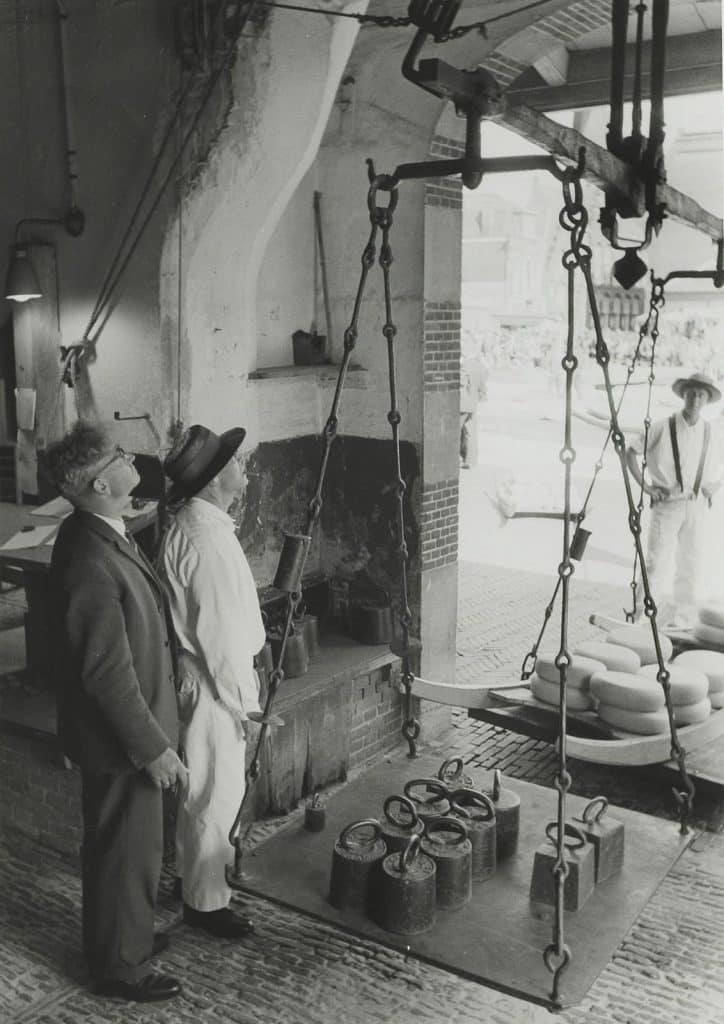 Interieur van de Waag op het Waagplein met kaasdragers en een kaasweger bij een weegschaal. Circa 1967 Fotocollectie Bosman.