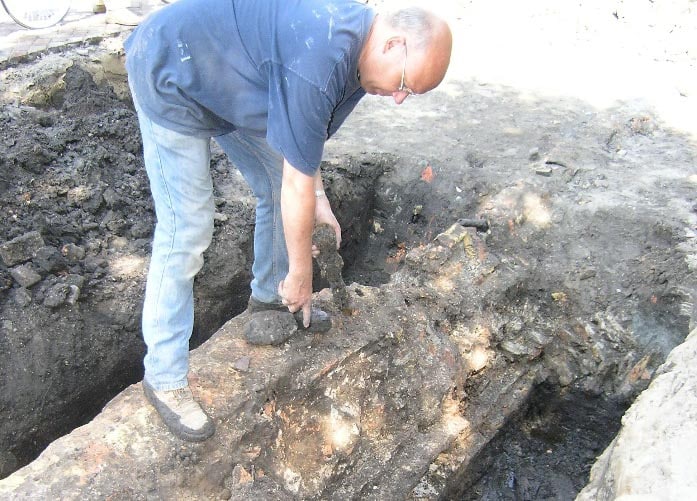 Rob Roedema met gietijzeren kanonskogel in de stadsmuur. Gevonden tijdens onderzoek aan de Wageweg tussen 2006 en 2008.