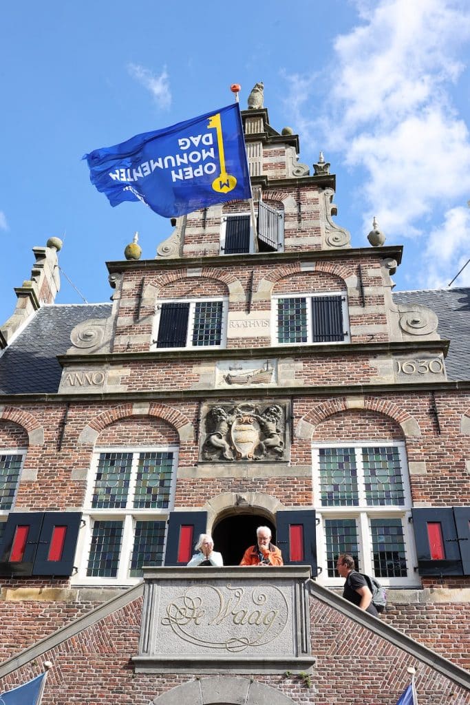 Raadhuis De Rijp met vlag en bezoekers op de trap