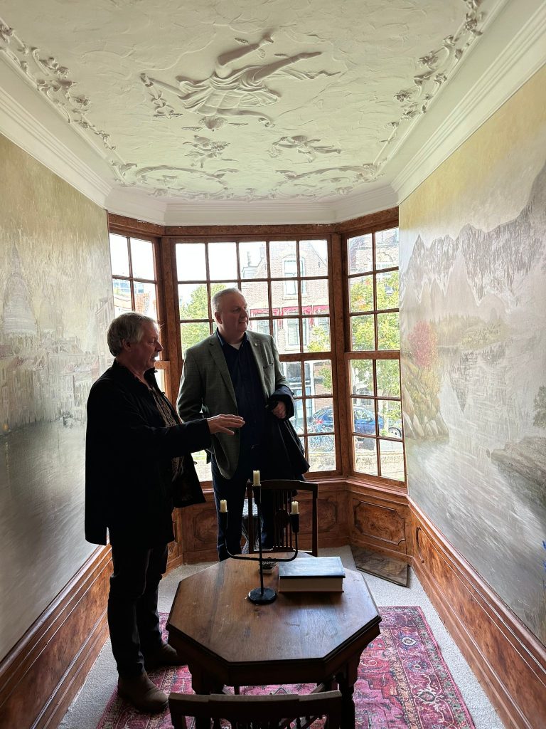 Wethouder Jan Hoekzema in de erker van het Smalste huisje met Rob de Vries