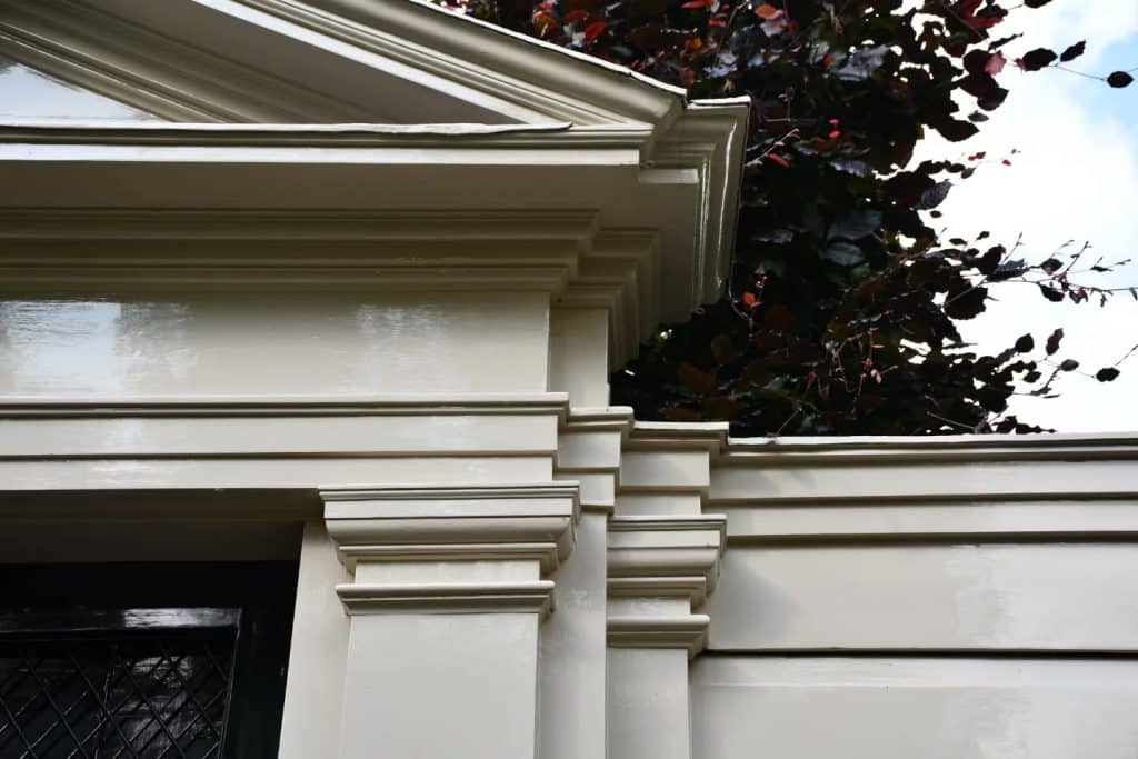 Kapitelen (bekroningen) op de schutting aan de Gedempte Baansloot. Boven de poort staat een klassiek driehoekig fronton.