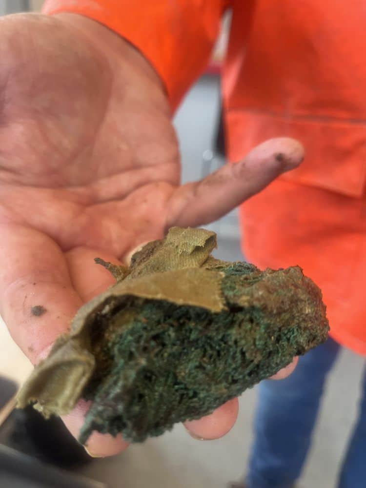 Textielresten en koperdraad worden steeds beter herkenbaar tijdens het spoelen door vrijwilliger Rob Roedema.