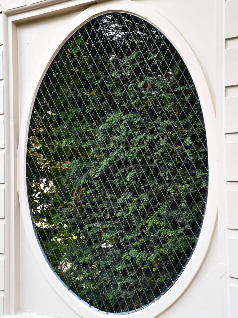 In de vakken zijn grote ovale openingen of medaillons gemaakt. Die zijn doorzichtig afgedicht met een rasterwerk van ijzerdraad.