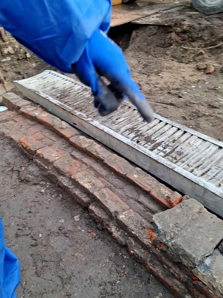 Afwatering met rechts stukje natuursteen als afdekking bij de opgraving in de Koorstraat.