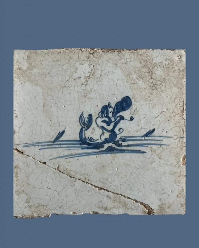 Tegel van zeemeerman Triton tevreden lurkend aan zijn tabakspijpje. Gevonden bij archeologisch onderzoek aan de Schermerweg in 2004.