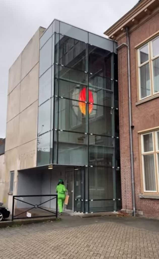 Klok binnen de Voormalige Ambachtsschool. De klok heeft een wisselende afbeelding die verlicht wordt.
