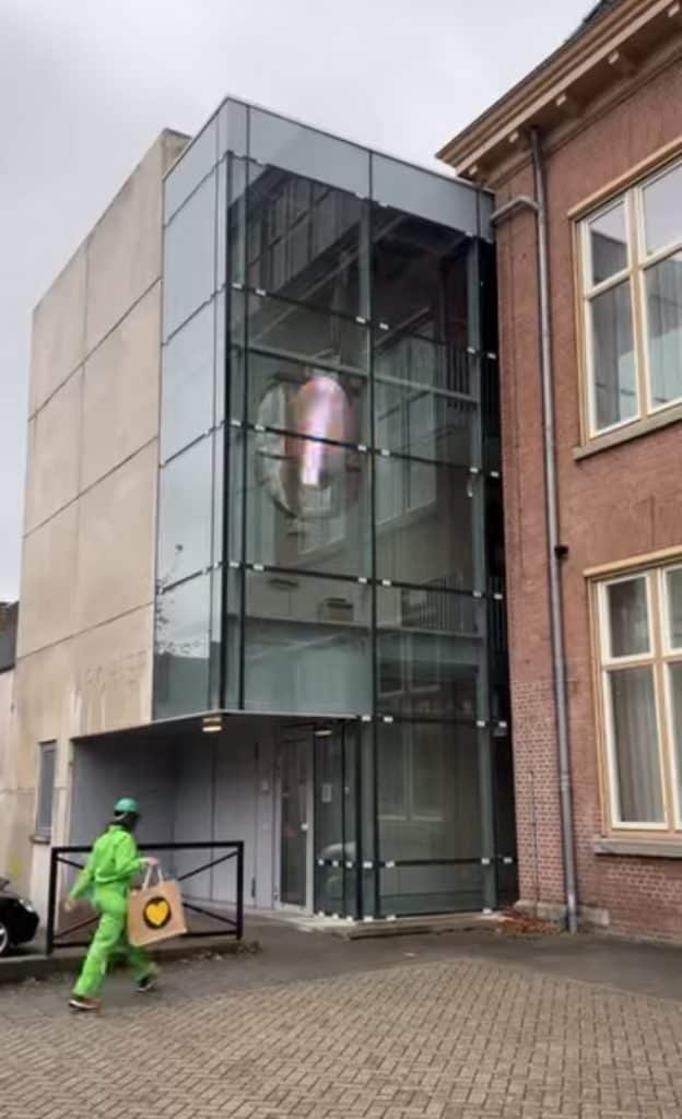 Klok binnen de Voormalige Ambachtsschool. De klok heeft een wisselende afbeelding die verlicht wordt.