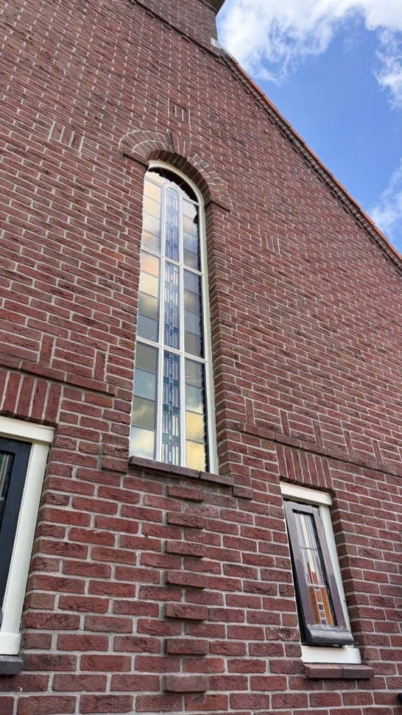 Geïsoleerde glas-in-loodraam van de onderwijzerswoning aan de Munnikenweg.