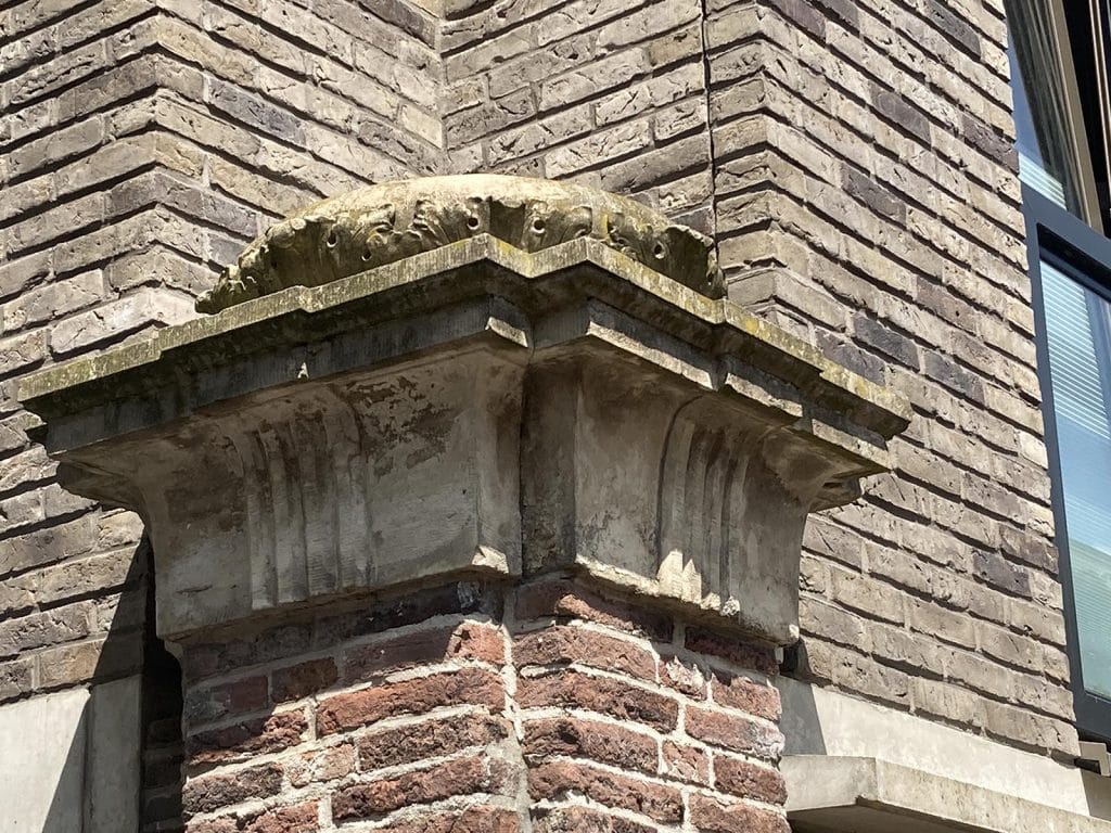 Hekpaal met een fraai gebeeldhouwde bekroning van zandsteen