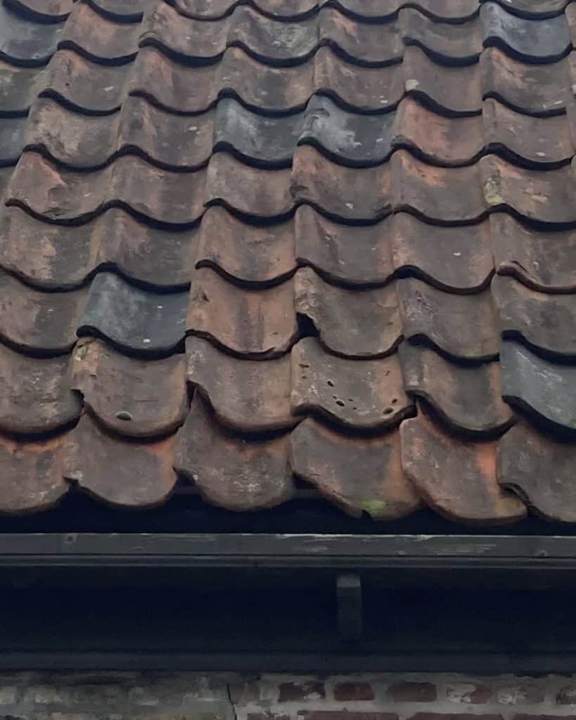 Links dekkende oude holle pannen op het dak van het houten huis aan de Kerkstraat.