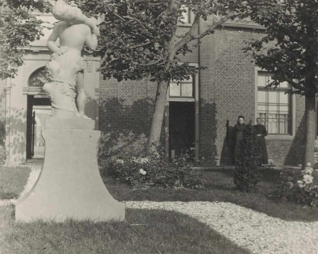 De binnenplaats van het Wildemanshof met links het beeld van de Wildeman rechts twee bewoonsters. Circa 1930.