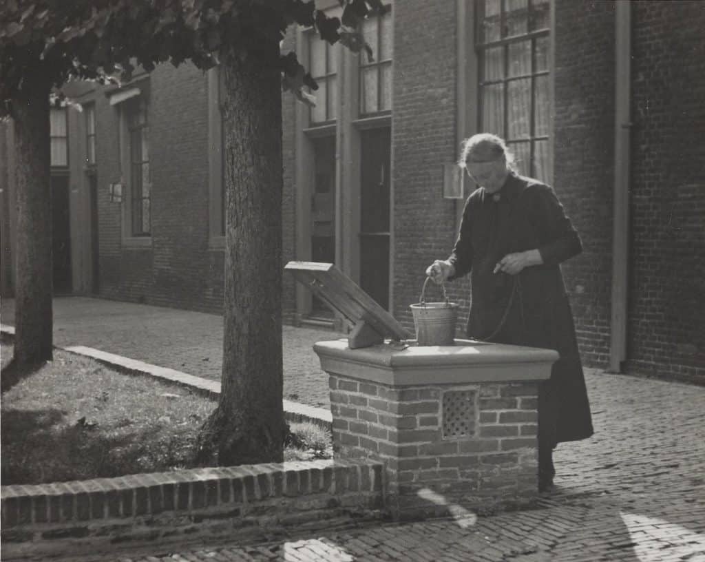 Een bewoonster bij de waterput van het Wildemanshof Foto AB Winters circa 1938