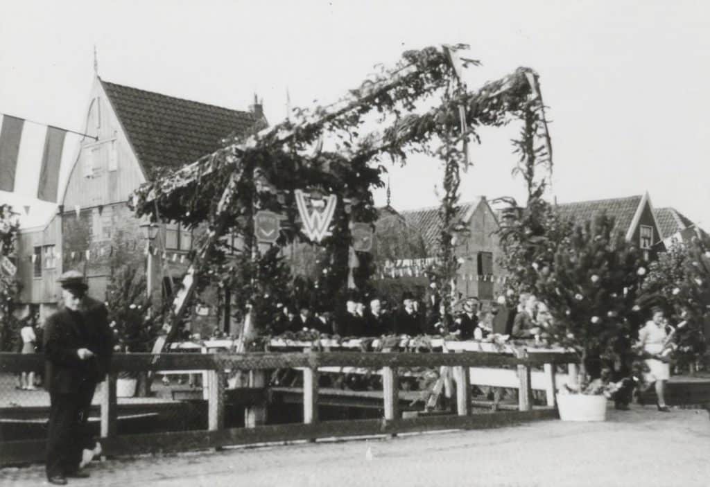 Prentbriefkaart Collectie Kaptein Circa 1945. Dit is een repro van de beeldzijde van een fotokaart uit de serie Bevrijdingsfeesten na de Tweede Wereldoorlog (september 1945). Er is een selectie van dertien kaarten gemaakt. Op deze afbeelding is de versierde Kralingerbrug te zien. De hoofdletter W staat voor Wilhelmina, de koningin.