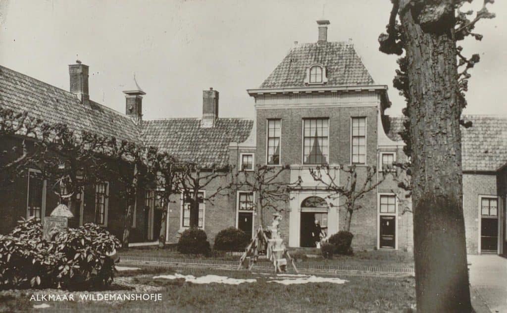 Prentbriefkaart. De tuin van het Wildemanshofje aan de Oudegracht. Er staat een wasrek in de tuin. Circa 1935.