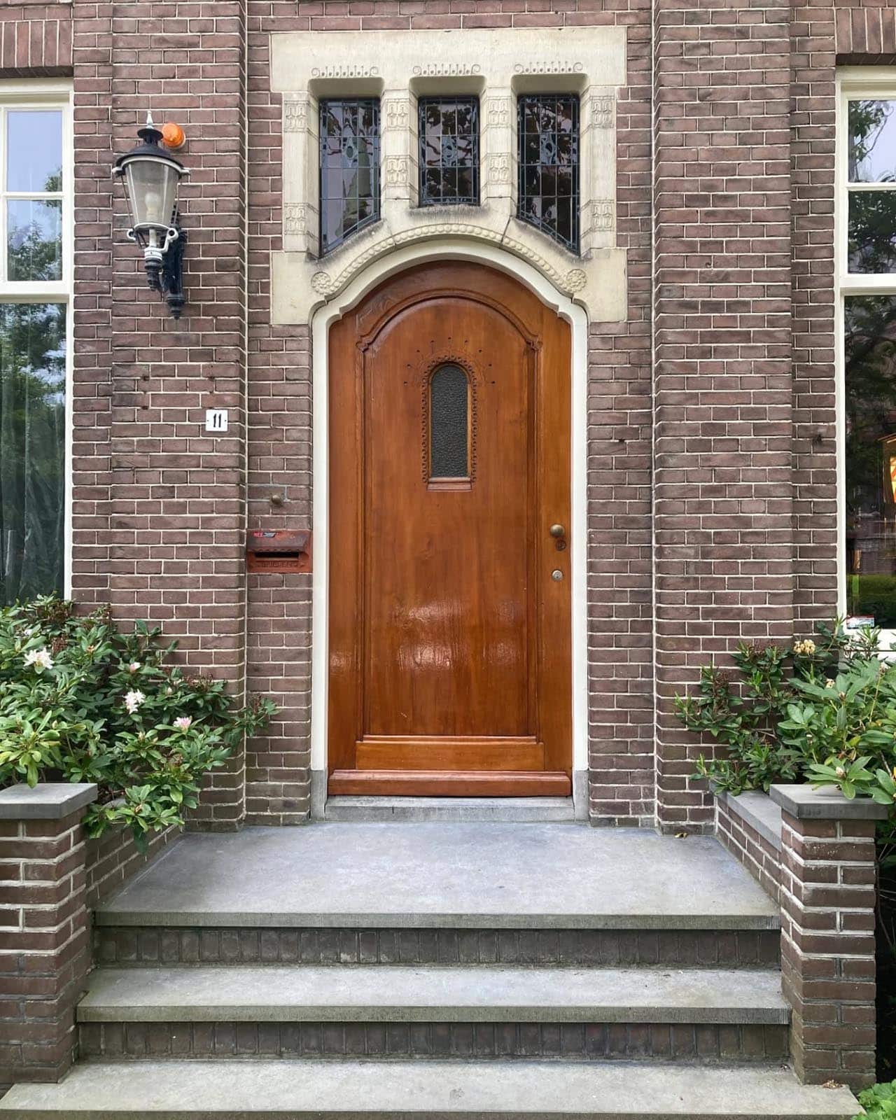 Fijn gedetailleerd natuursteen rond de voordeur met houtsnijwerk aan de Nassaulaan.