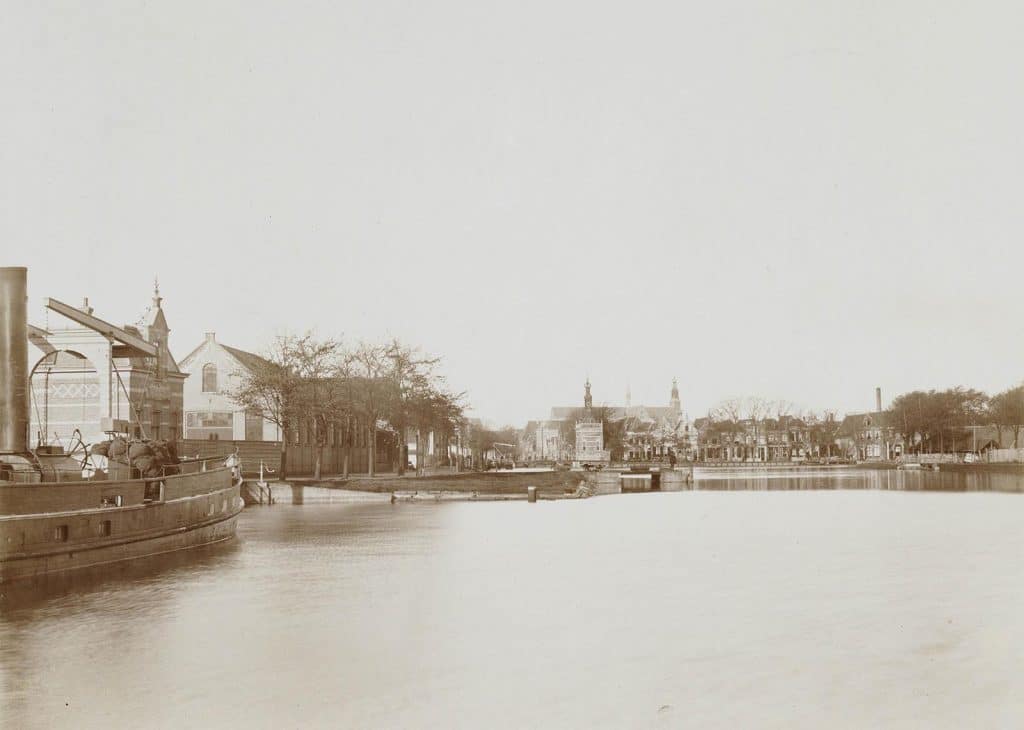 Links de Voormeer met vooraan de ijzerfabriek en de Brugwachterswoning. In het midden de Accijnstoren. 1893.