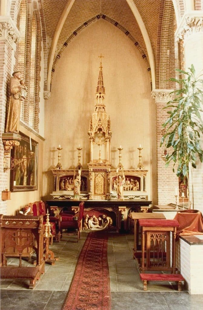 Neogotische altaar met een zwart marmeren blad. Tussen de groen marmeren zuiltjes een gepolychromeerde beeldengroep van de Graflegging. Links en rechts hiervan een engel. Foto J. Elsinga 1992.