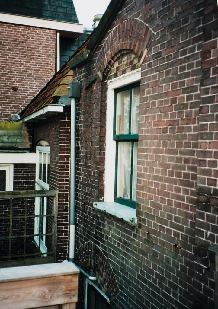 Raam op de verdieping van de Brugwachterswoning aan de Eilandswal. Boven het raam zit een sierlijke segmentboog met gekleurde accenten. Foto A. Schoots 2002.