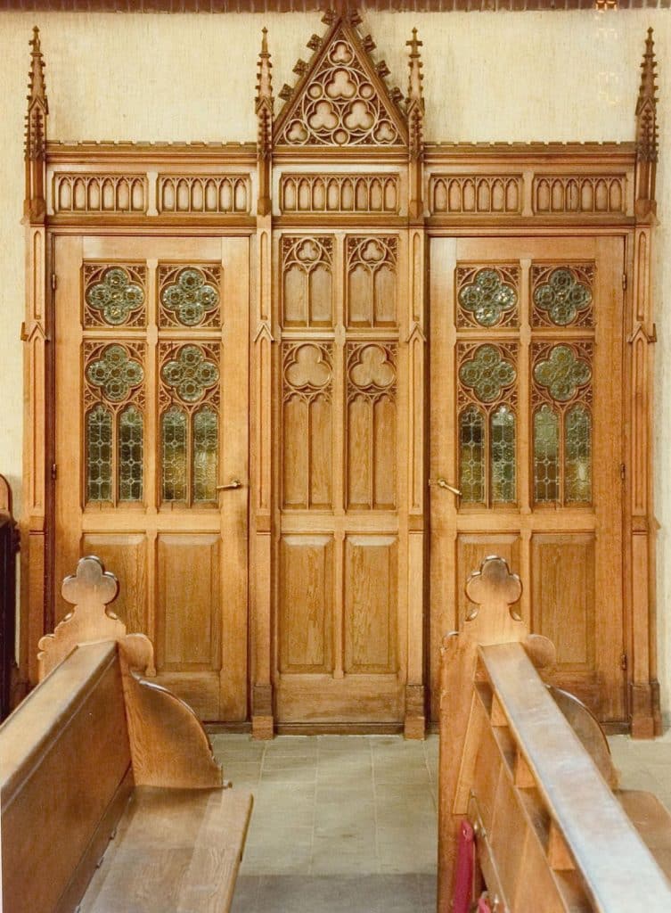 Rijkgesneden neogotische eikenhouten biechtstoelen achter twee paneeldeuren met glas-in-loodramen. Foto J. Elsinga 1992.