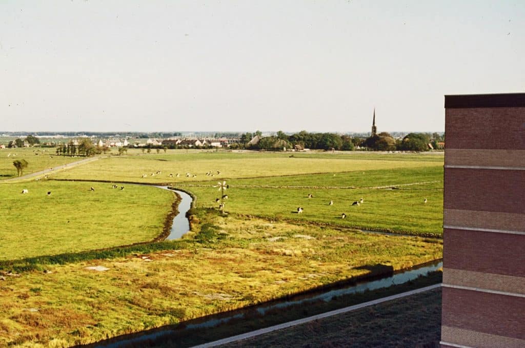 Zicht over het weiland vanaf een flatgebouw op de Sint Laurentiuskerk in Oudorp. Foto J. Elsinga Circa 1980.