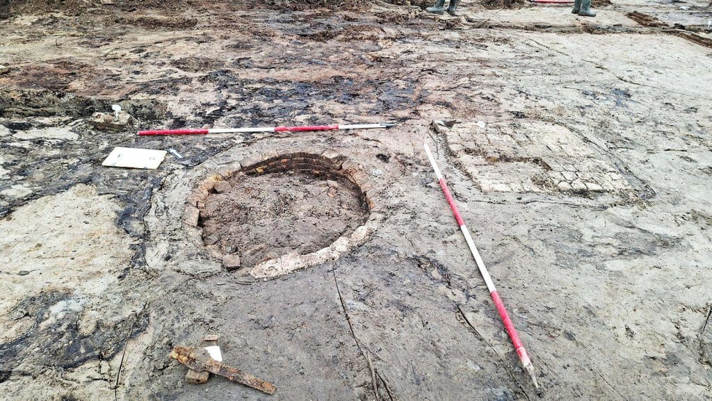 In het opgravingsvlak zien we de contouren van een waterput met daarnaast één van de vier funderingspoeren.