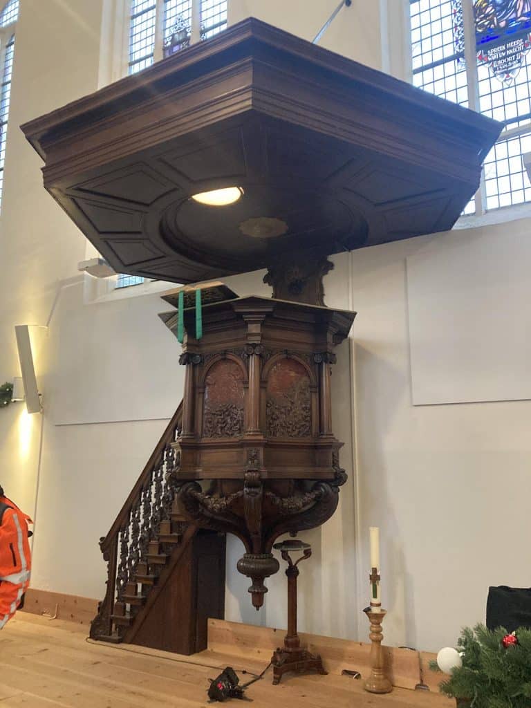 De preekstoel heeft een zeshoekige kuip waar de spreker kan staan. In de wanden zijn Bijbelse voorstellingen uitgesneden.